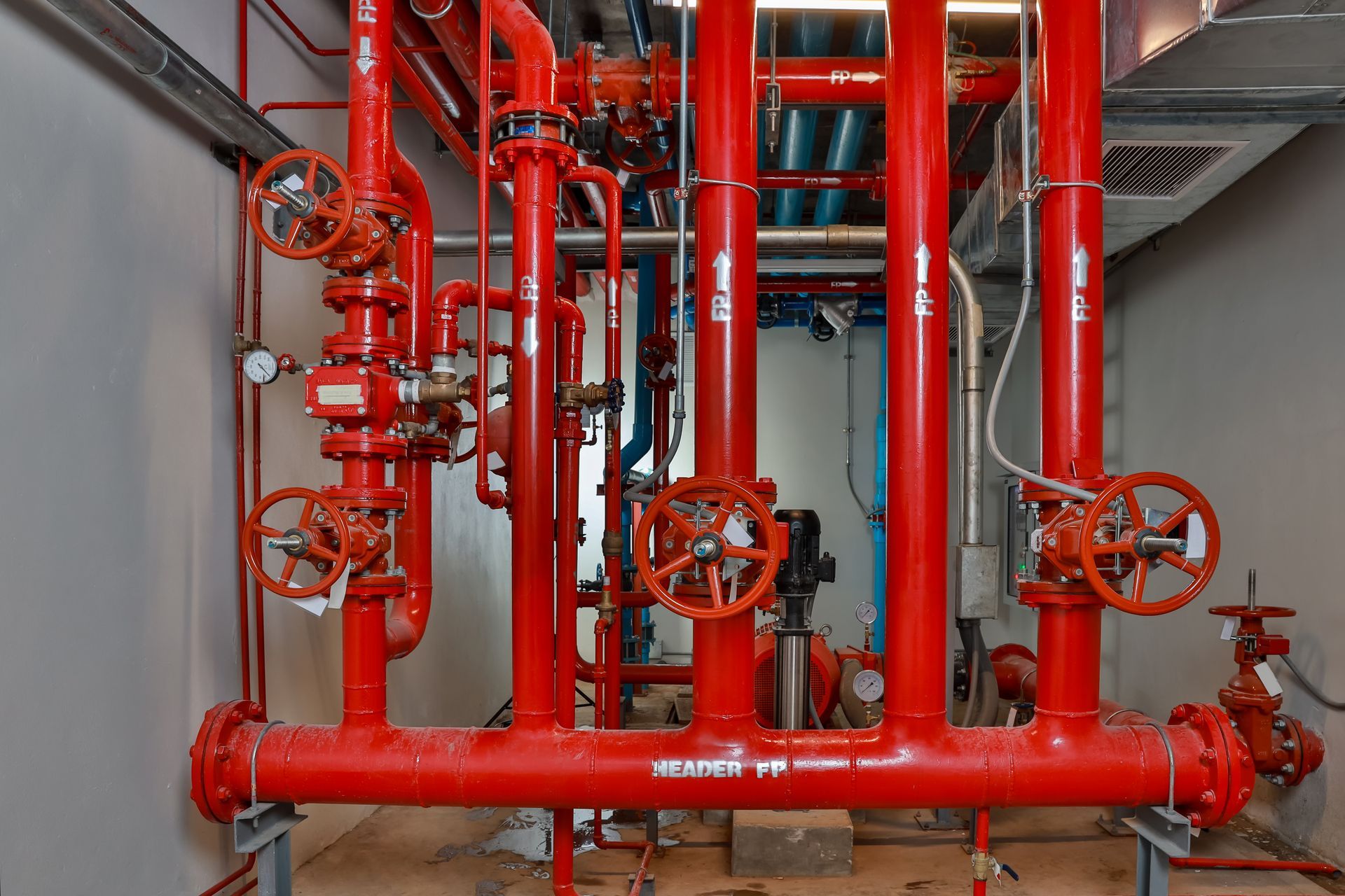 Red fire suppression pipes and valves in an equipment room.