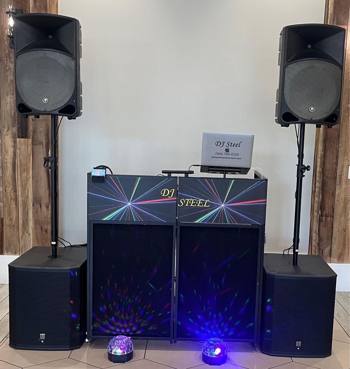 DJ booth with colorful lights and speakers in a dark room with a draped backdrop