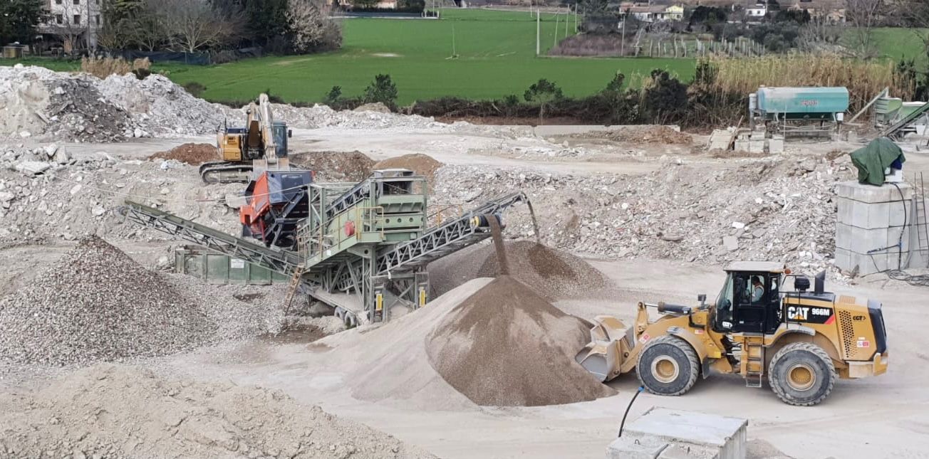 Un mucchio di rocce viene caricato su un nastro trasportatore in una cava.