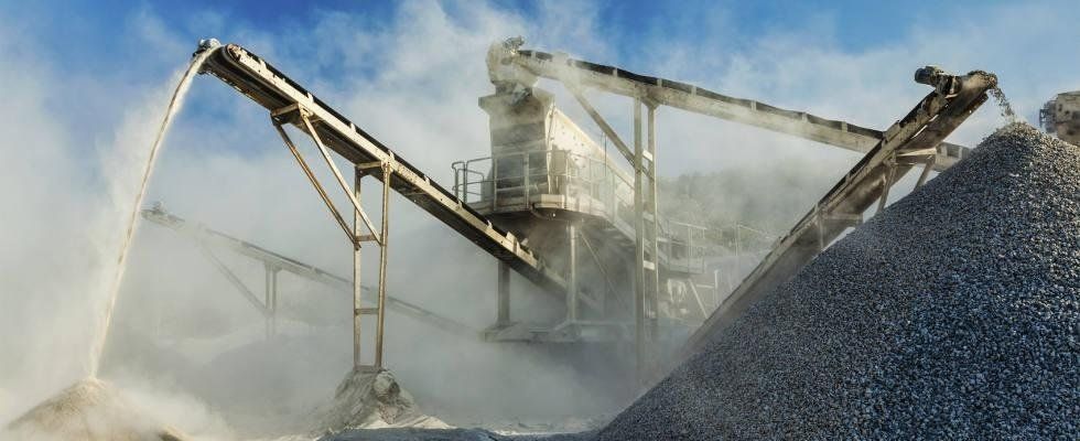 Un mucchio di rocce viene caricato su un nastro trasportatore in una cava.