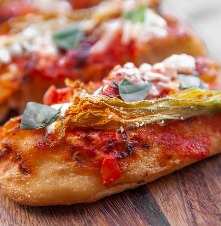 A close up of a pizza on a wooden cutting board.