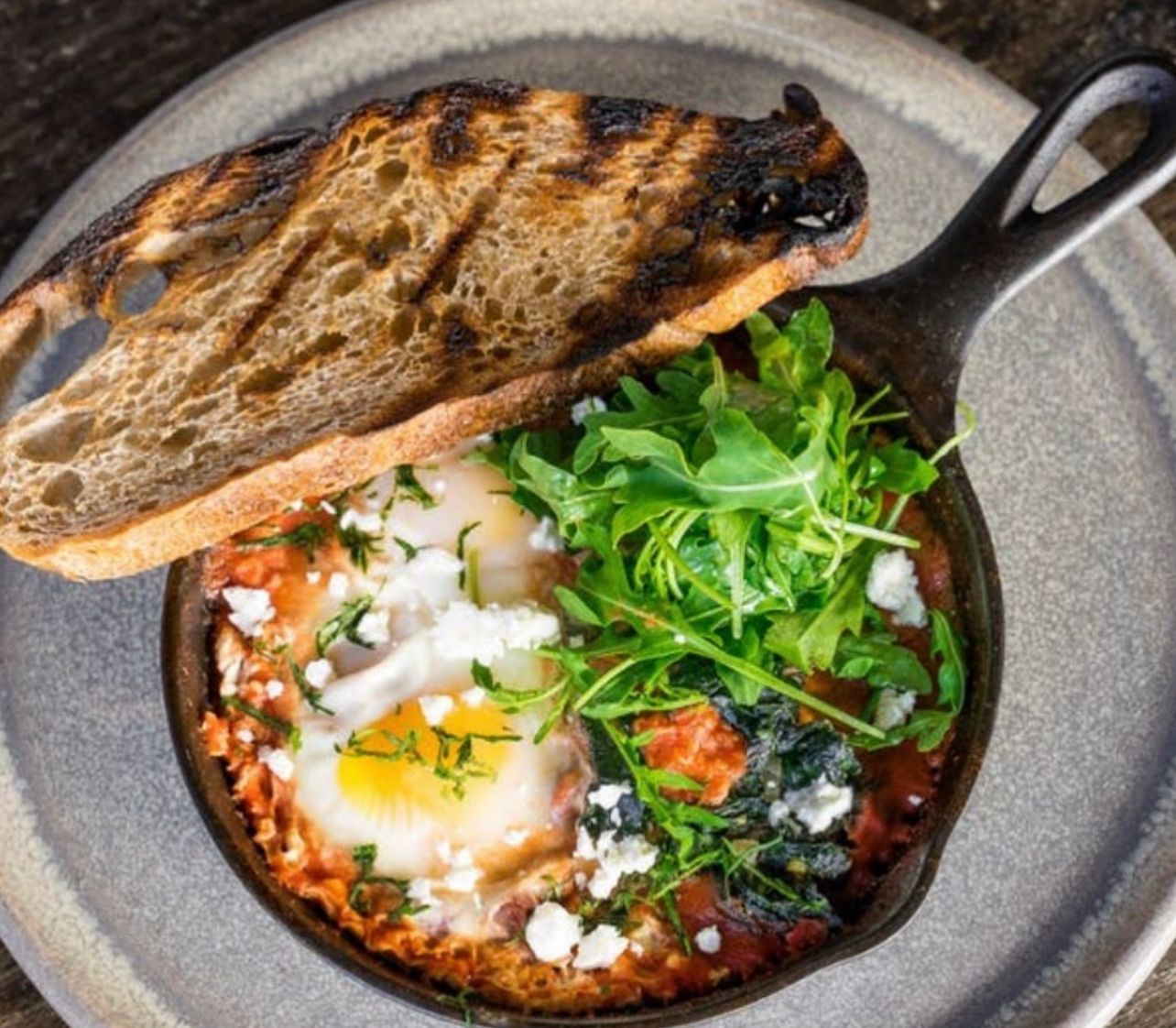 A skillet filled with food and a piece of bread on a plate.