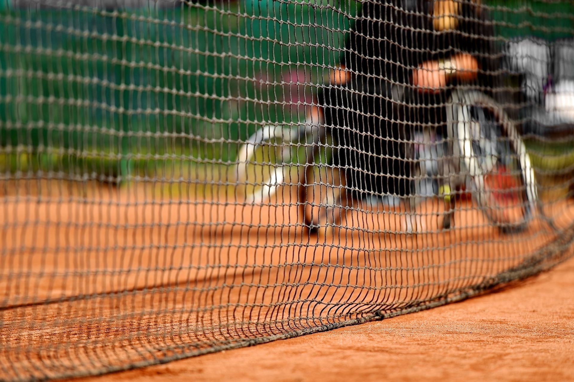 A person in a wheelchair is playing tennis on a tennis court.