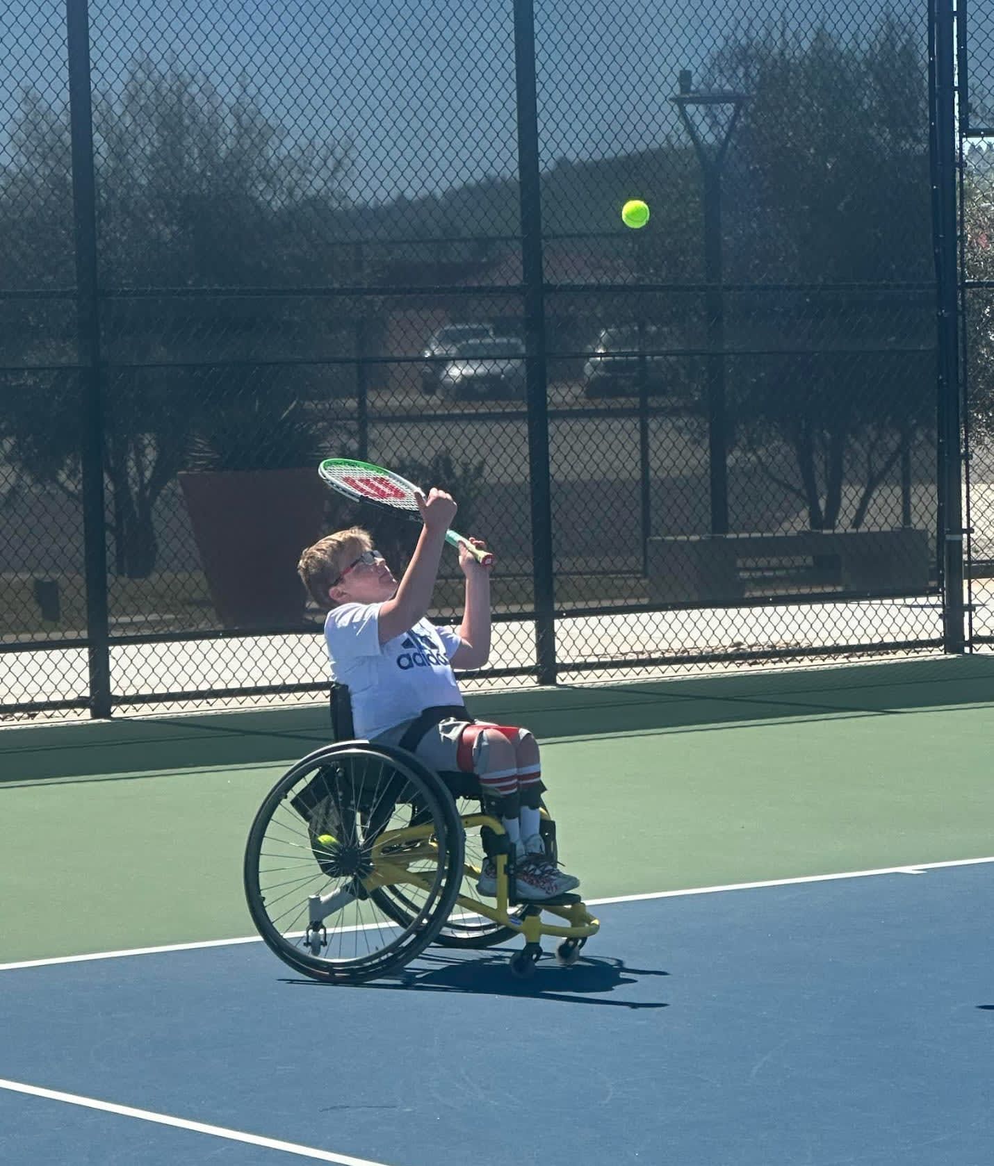 A man in a wheelchair is hitting a tennis ball