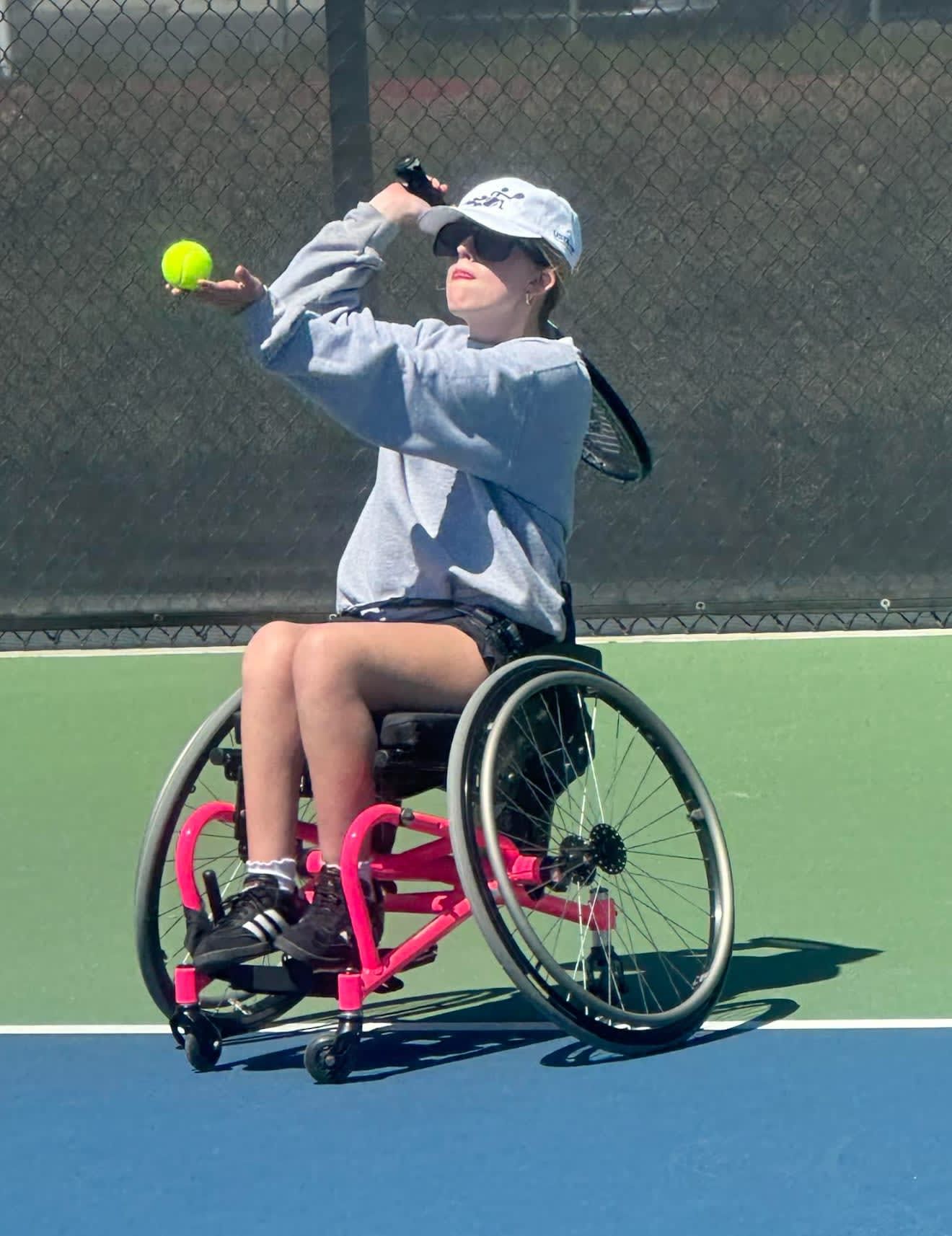 A woman in a wheelchair is playing tennis