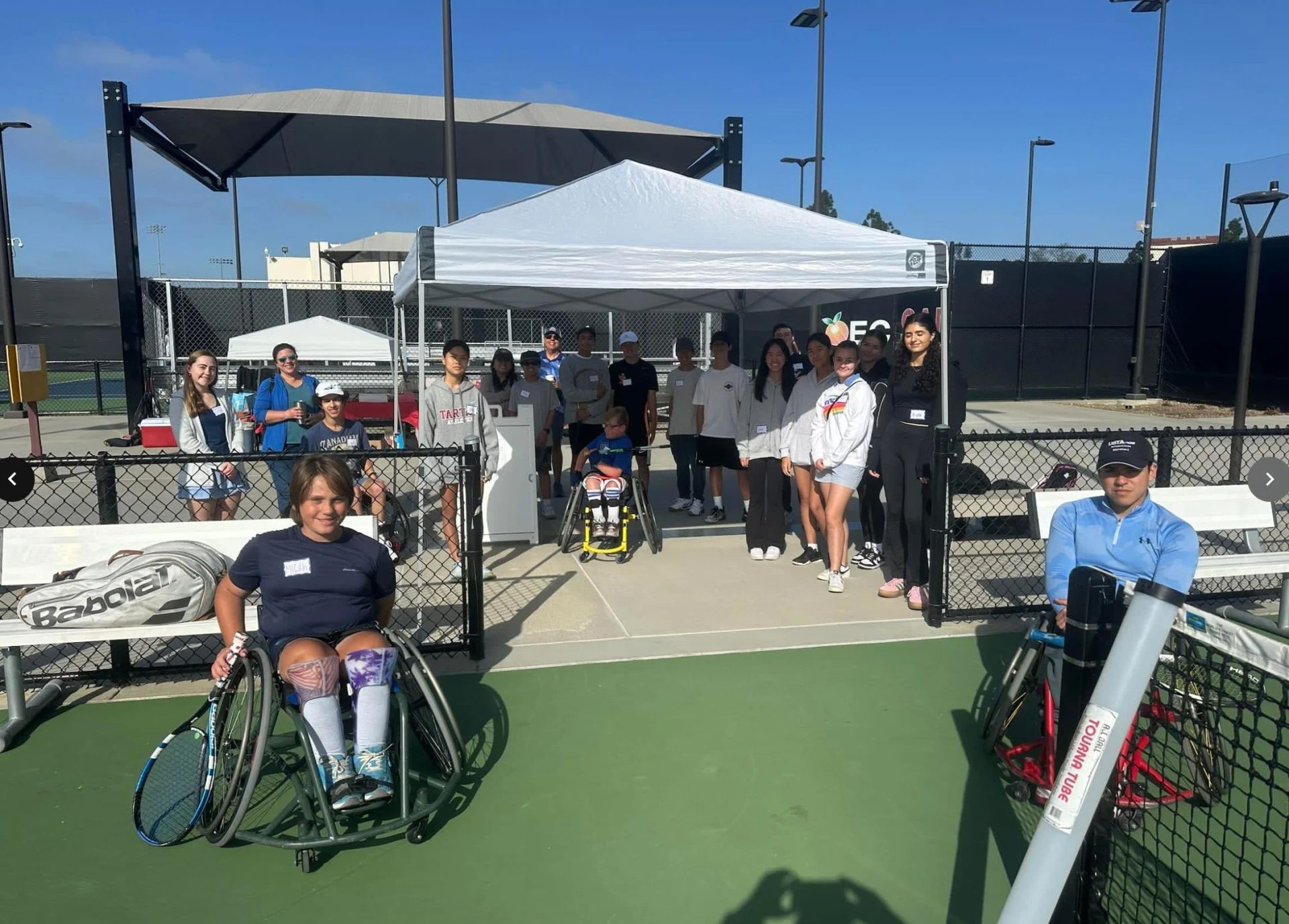 A woman in a wheelchair is holding a tennis racquet on a tennis court.