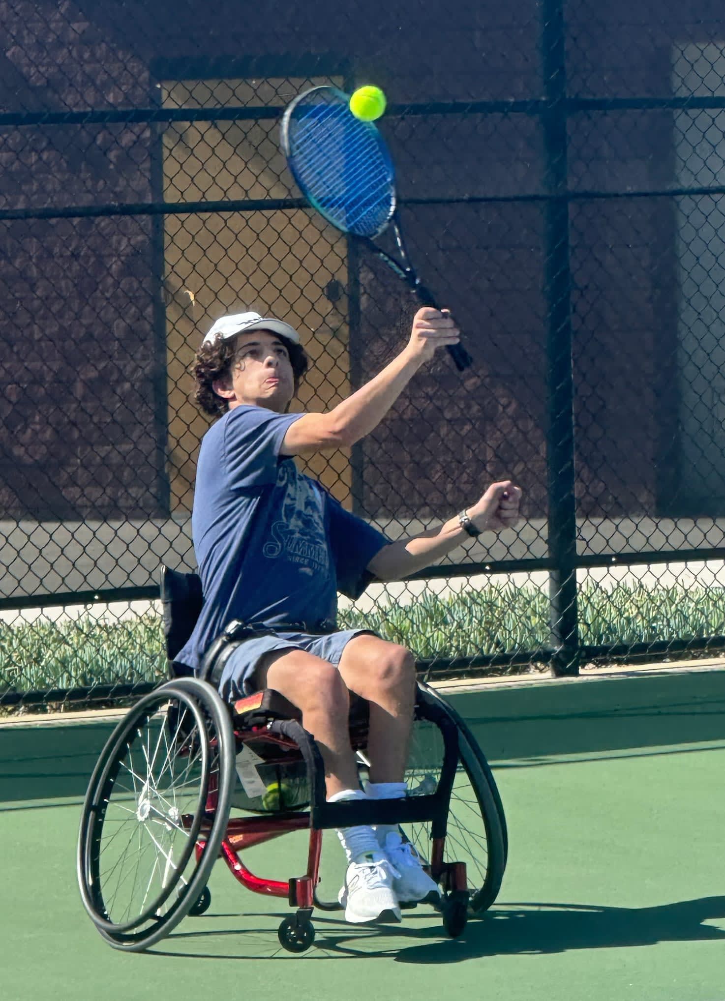 A person in a wheelchair is playing tennis