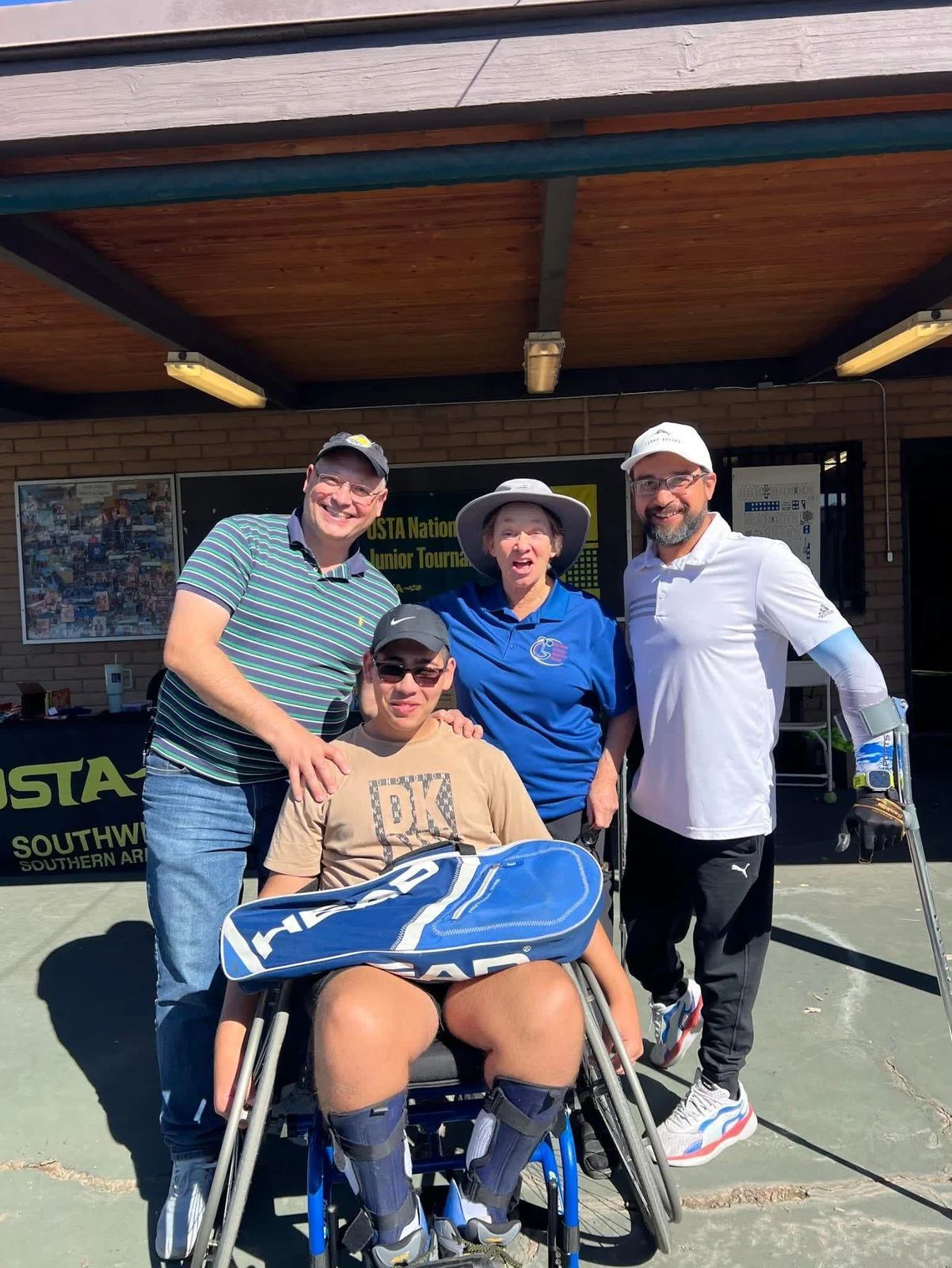 A group of people are posing for a picture with a man in a wheelchair.