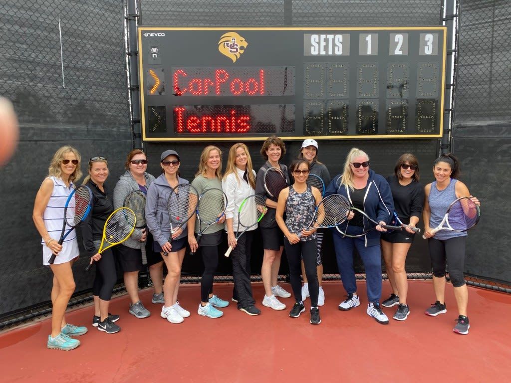 A group of women are posing for a picture on a tennis court.