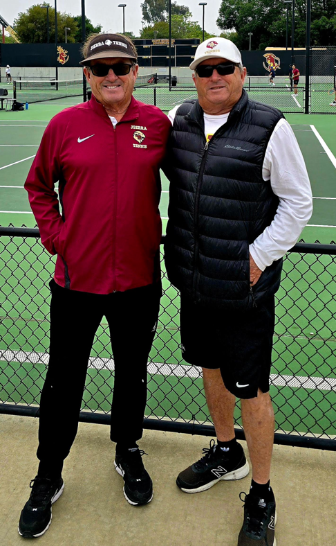 Two men standing next to each other on a tennis court