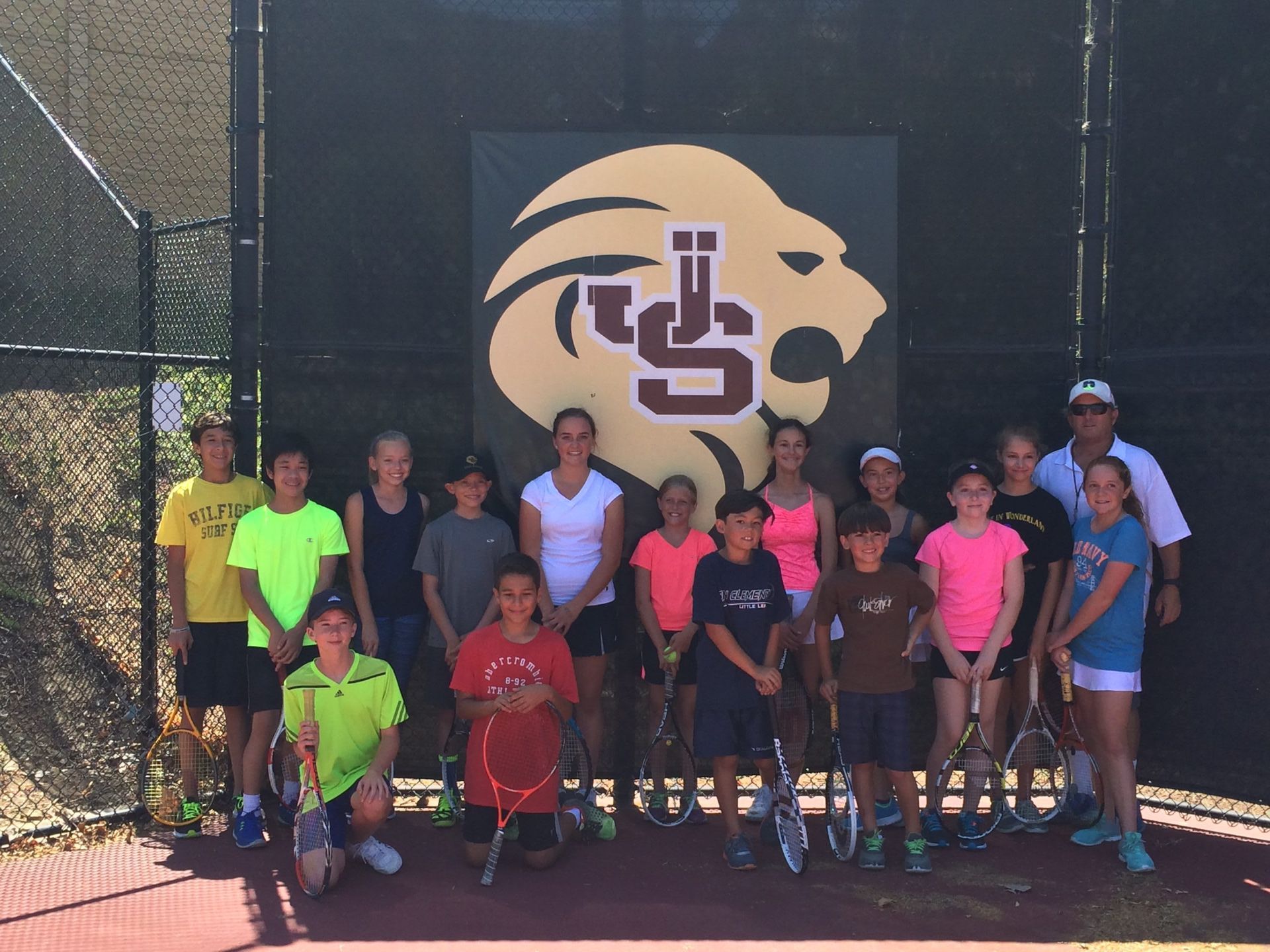 A group of kids are posing for a picture in front of a lion logo