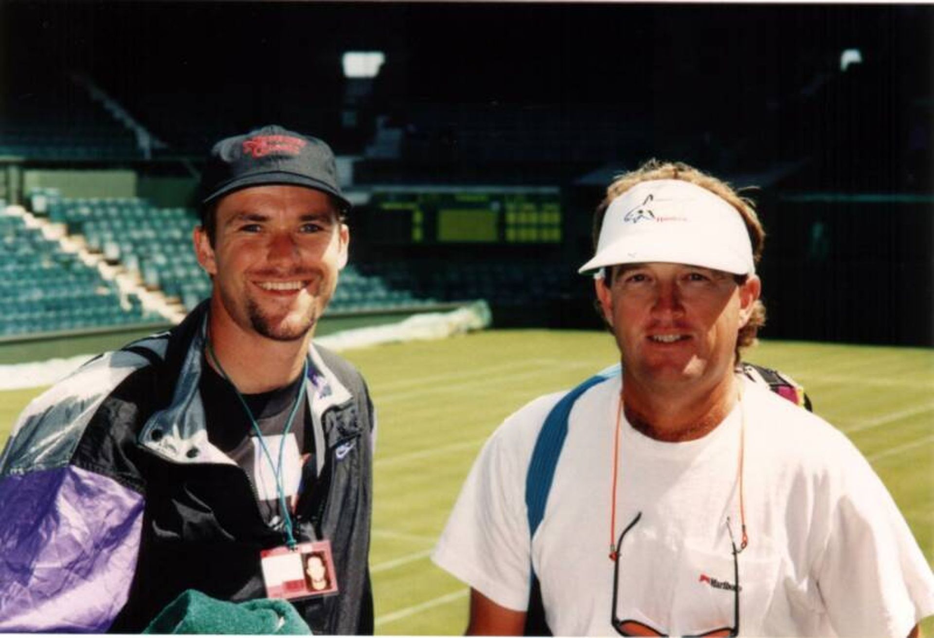 Two men are posing for a picture on a tennis court
