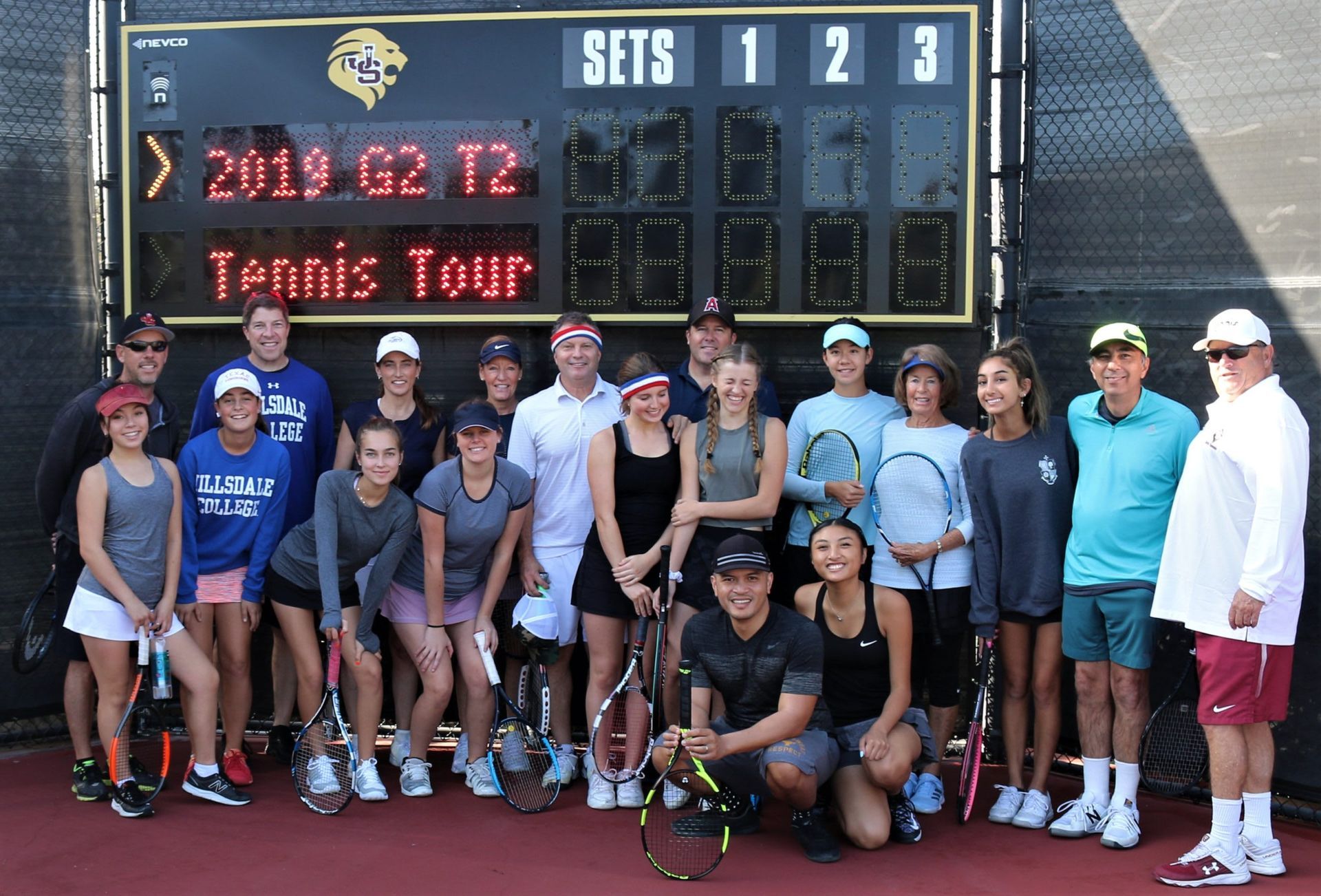 A group of people standing in front of a tennis scoreboard