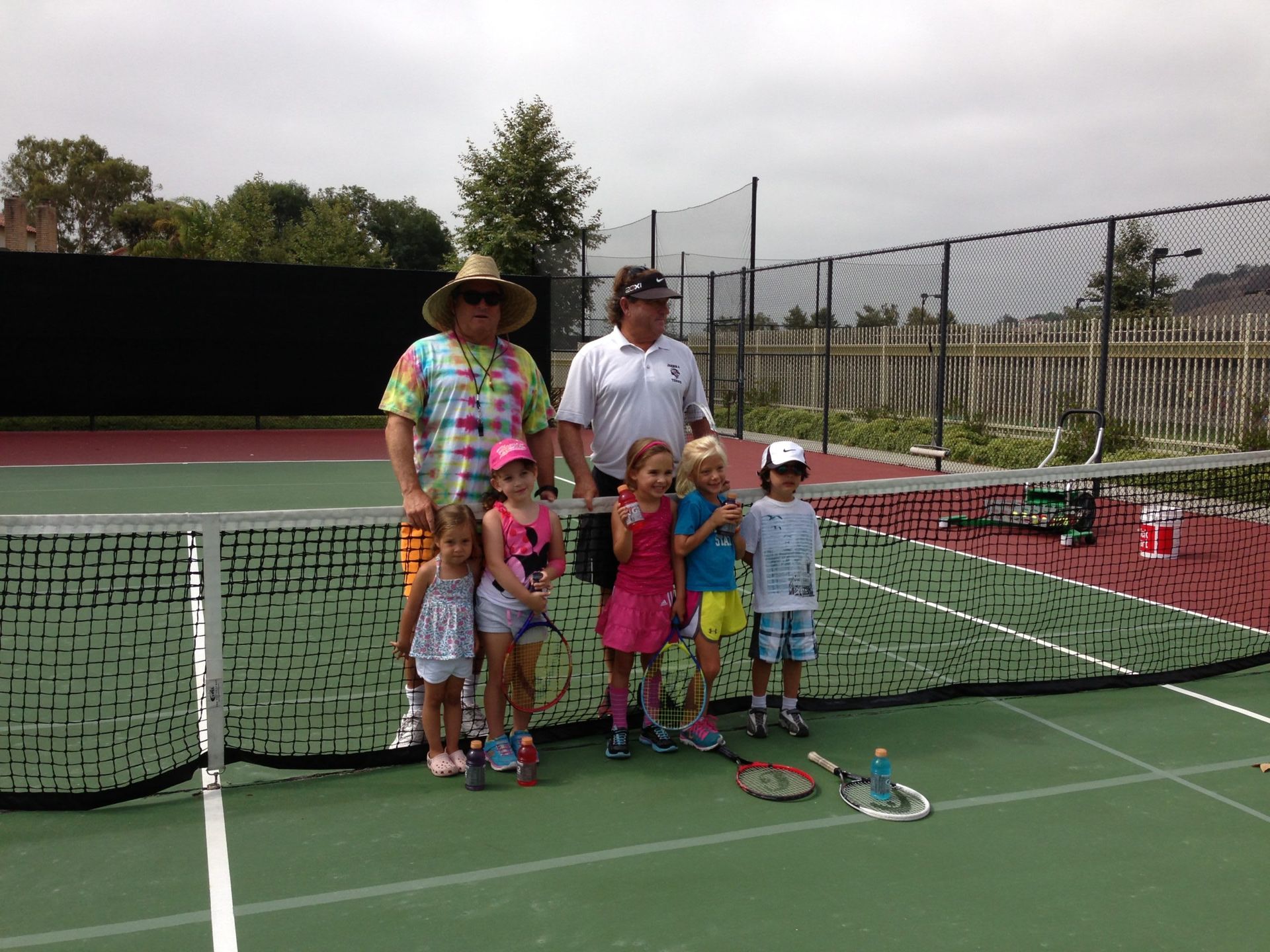 A group of people are posing for a picture on a tennis court.