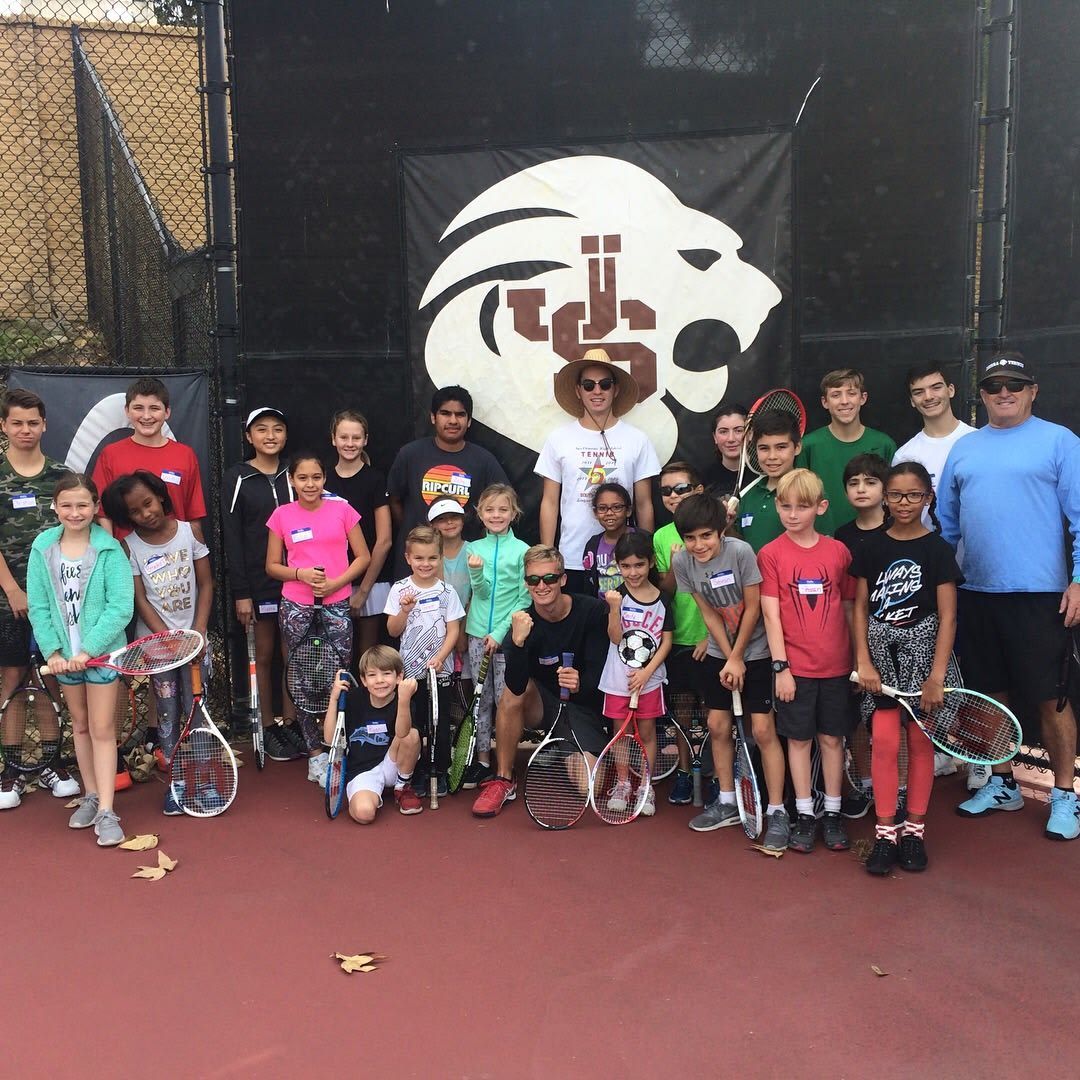 A group of people posing for a picture on a tennis court