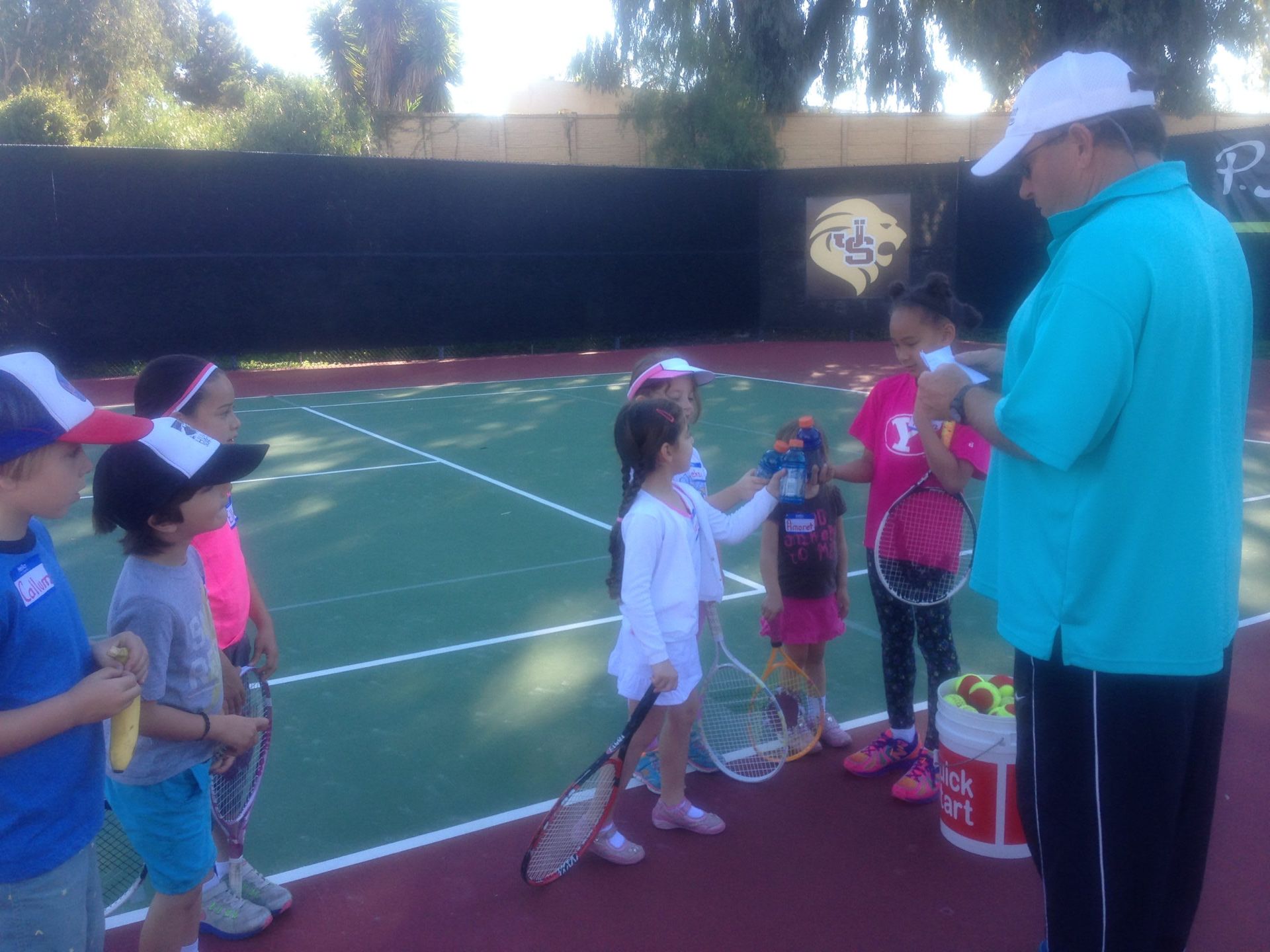 A group of children are standing on a tennis court
