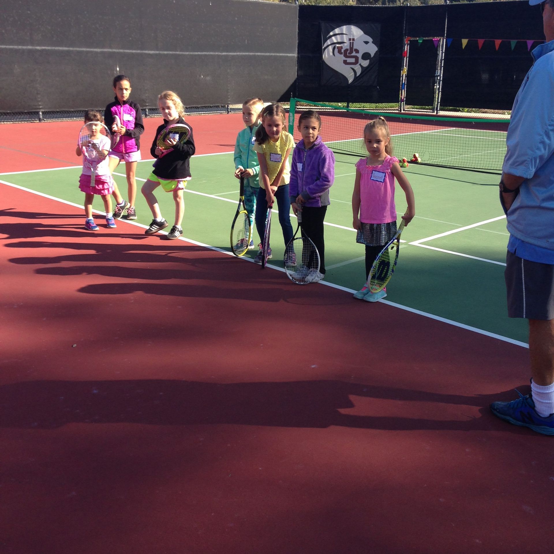 A group of children holding tennis rackets on a tennis court