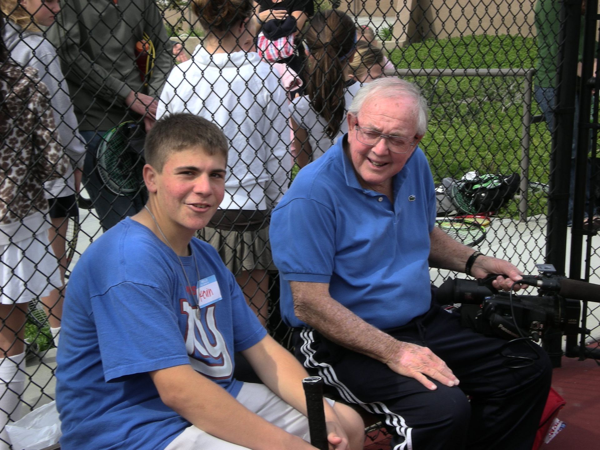 A boy wearing a kc shirt sits next to an older man