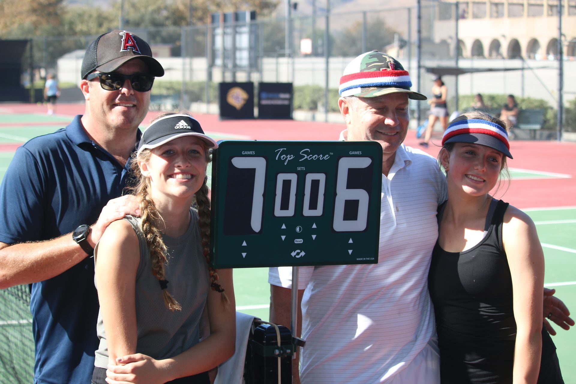 A group of people standing on a tennis court holding a sign that says 7006