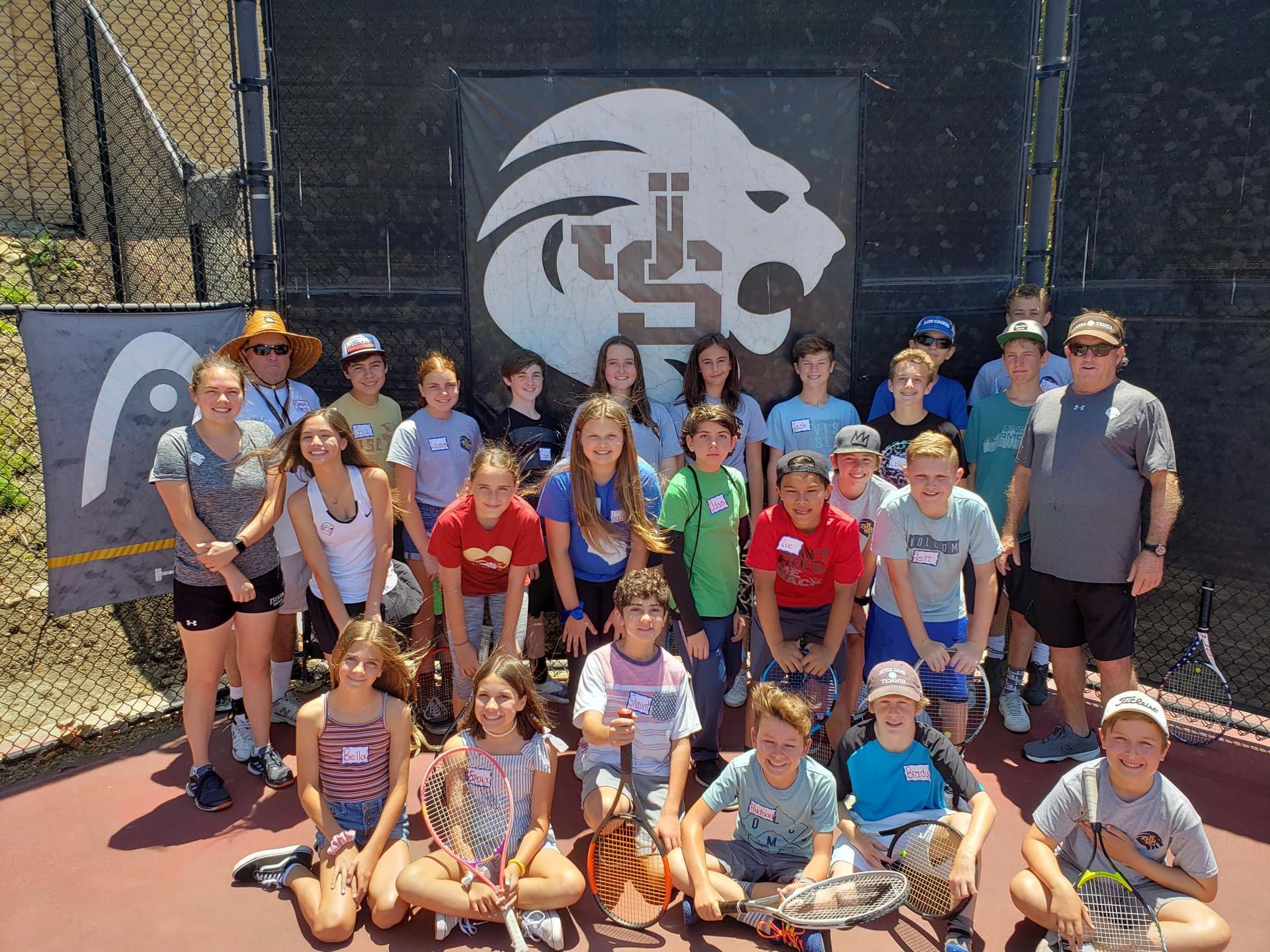 A group of children are posing for a picture on a tennis court.