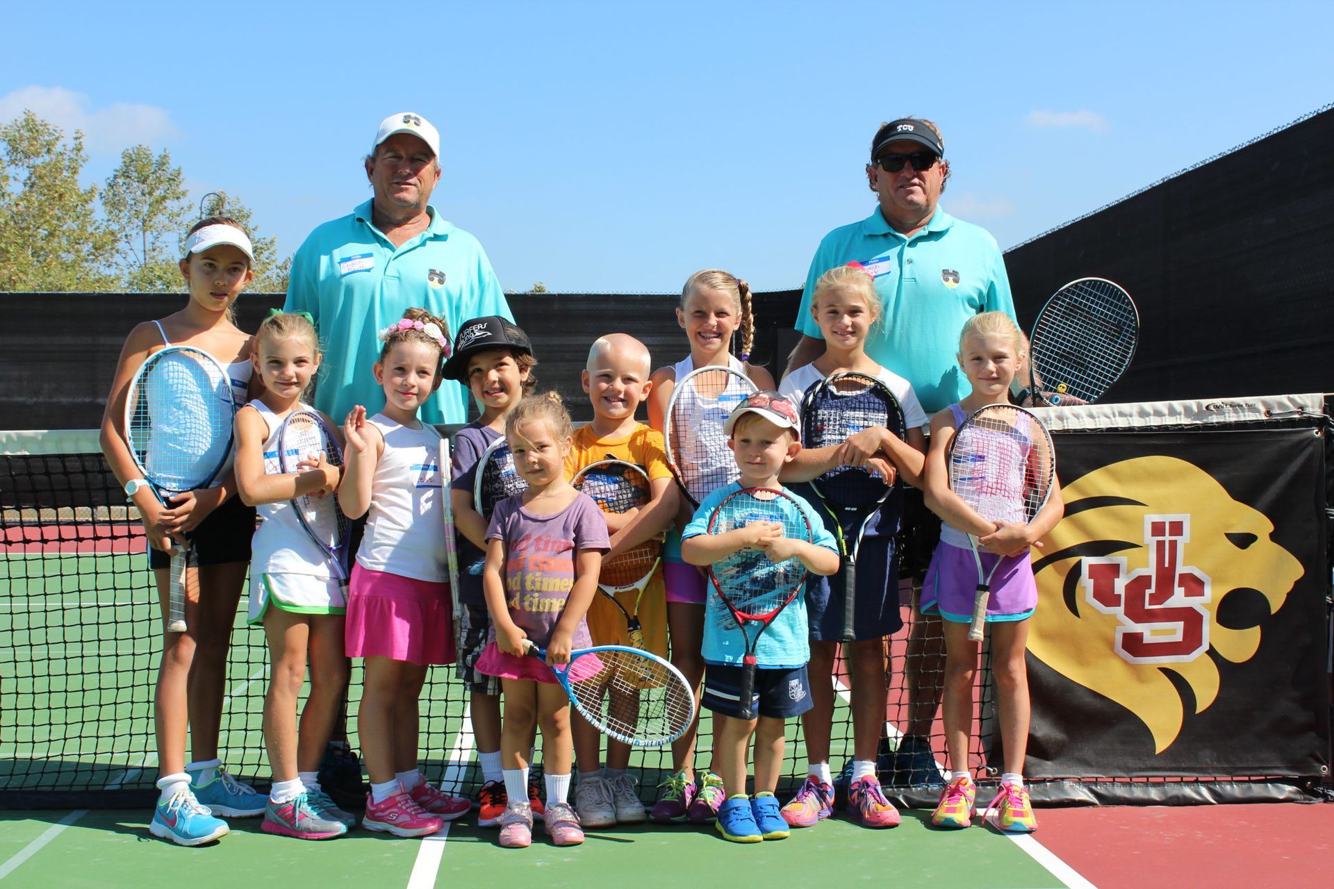 A group of children are posing for a picture on a tennis court