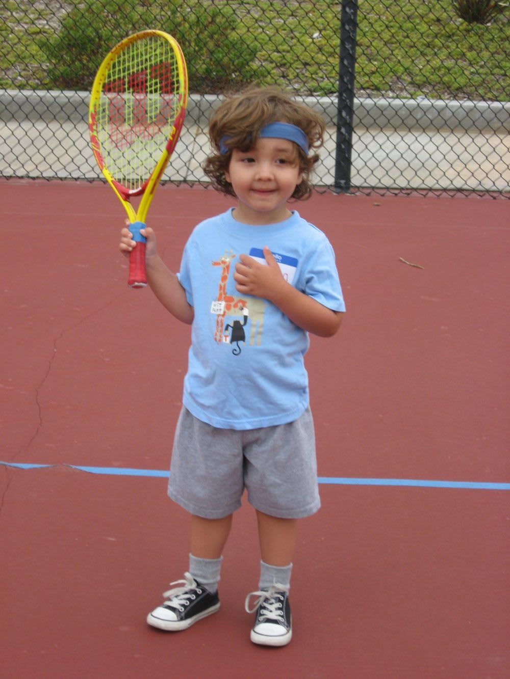 A young boy is holding a tennis racquet on a tennis court