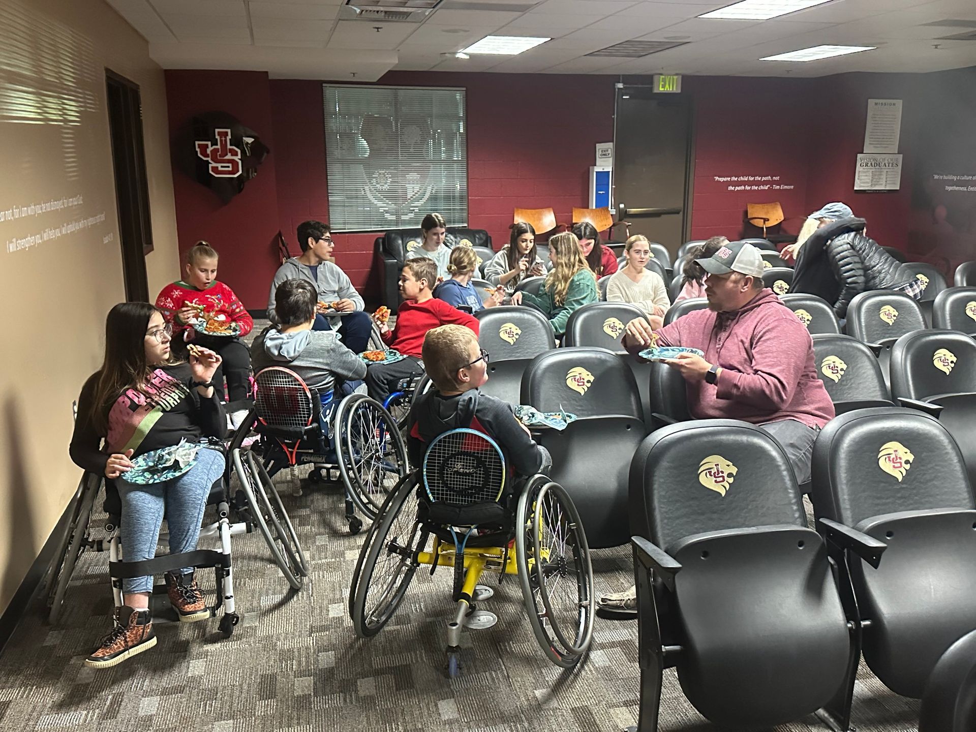 A group of people in wheelchairs are sitting in an auditorium.