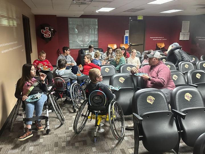A group of people in wheelchairs are sitting in an auditorium.