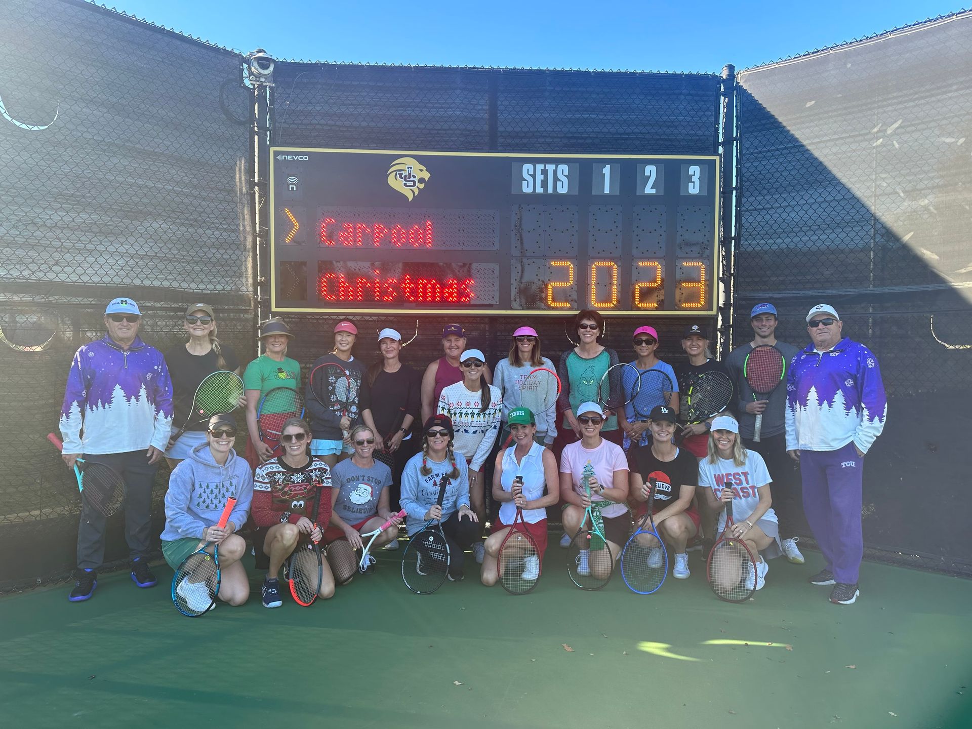 A group of people are posing for a picture in front of a scoreboard.
