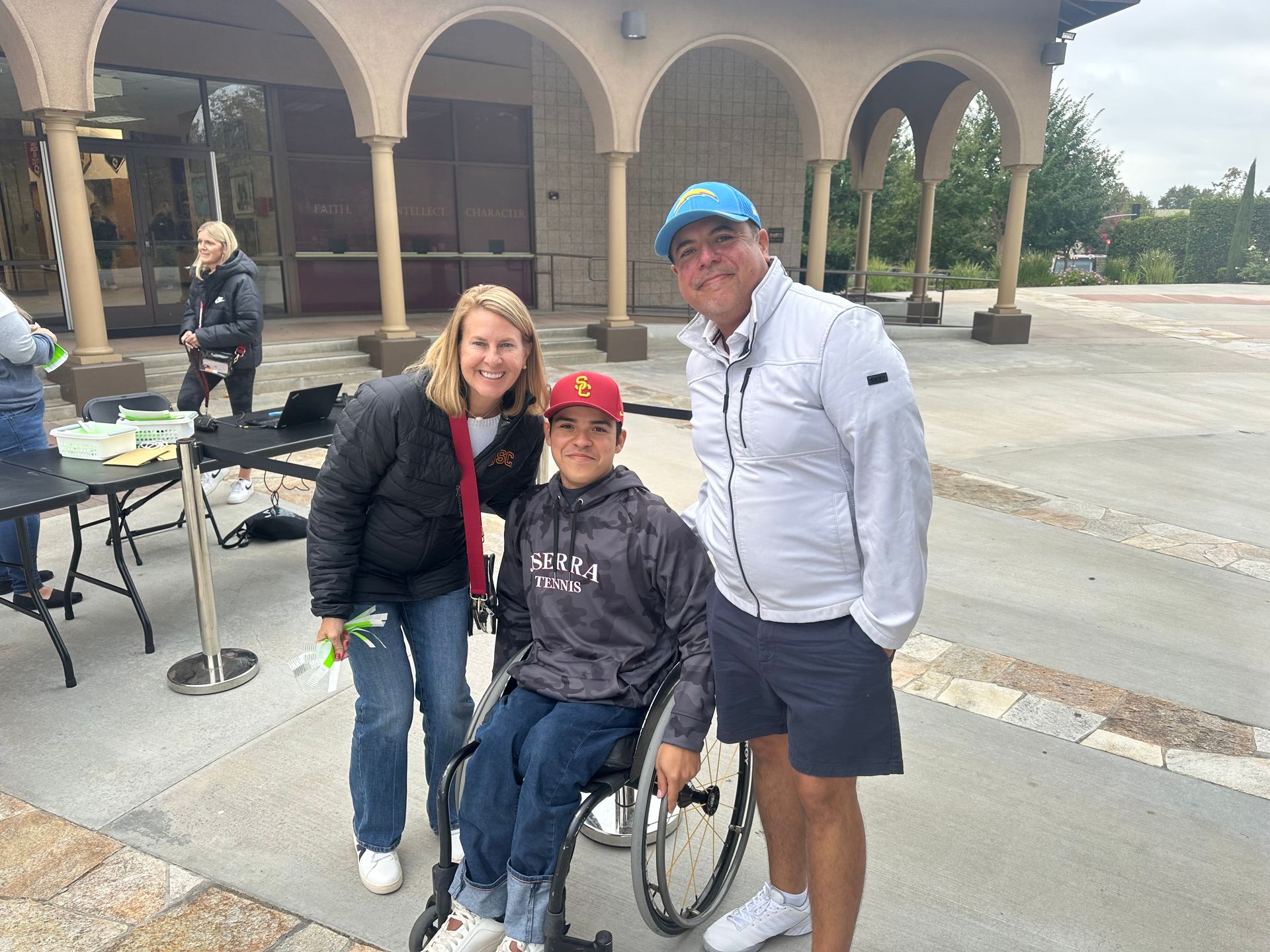 A man and woman are standing next to a boy in a wheelchair.
