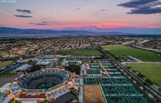 An aerial view of a stadium and tennis courts at sunset.