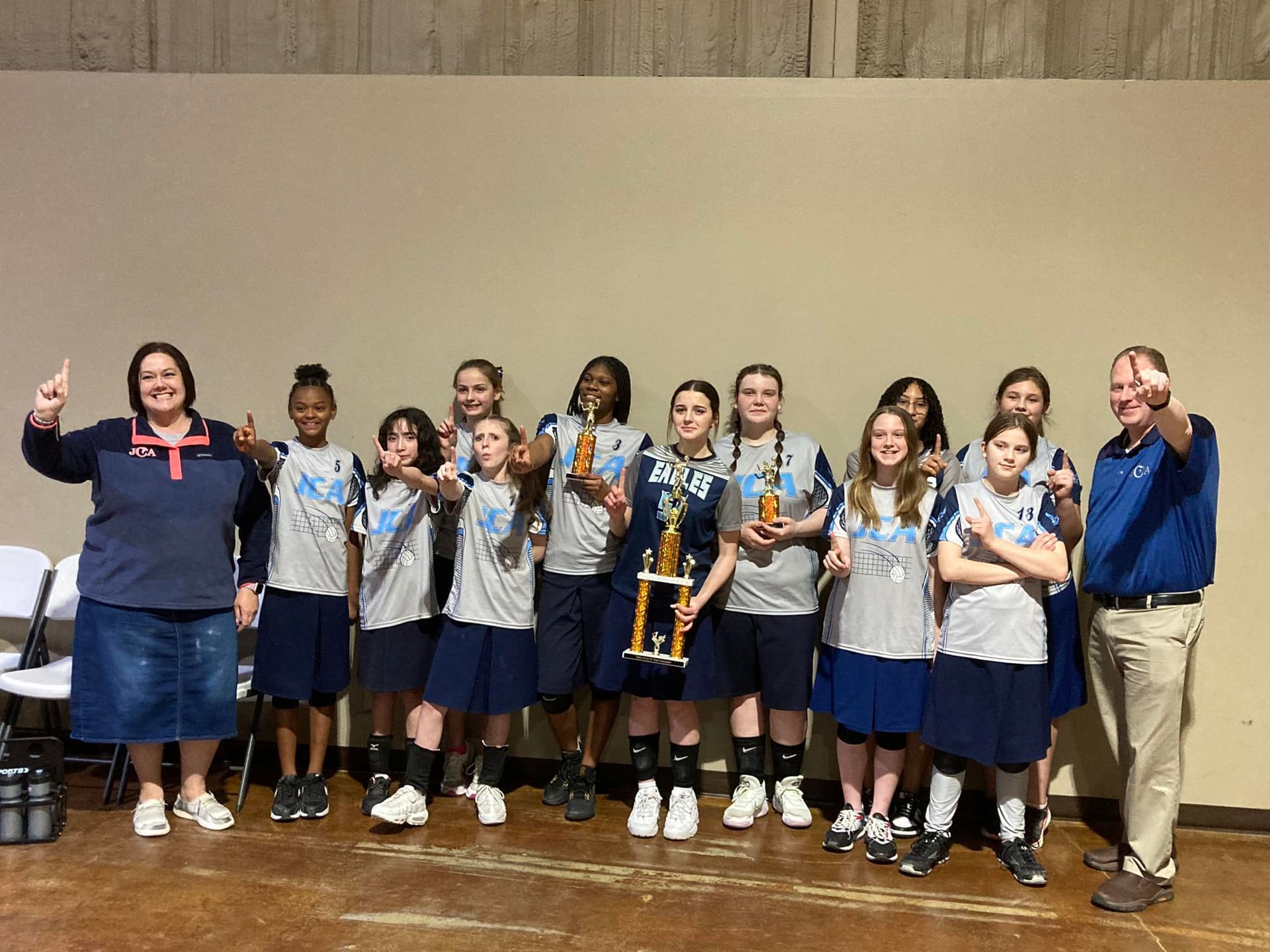 A group of young girls are posing for a picture while holding trophies.