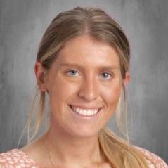 A woman in a pink shirt is smiling for a picture.