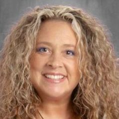 A woman with curly hair is smiling for the camera.