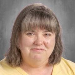 The woman is wearing a yellow shirt and smiling for the camera.