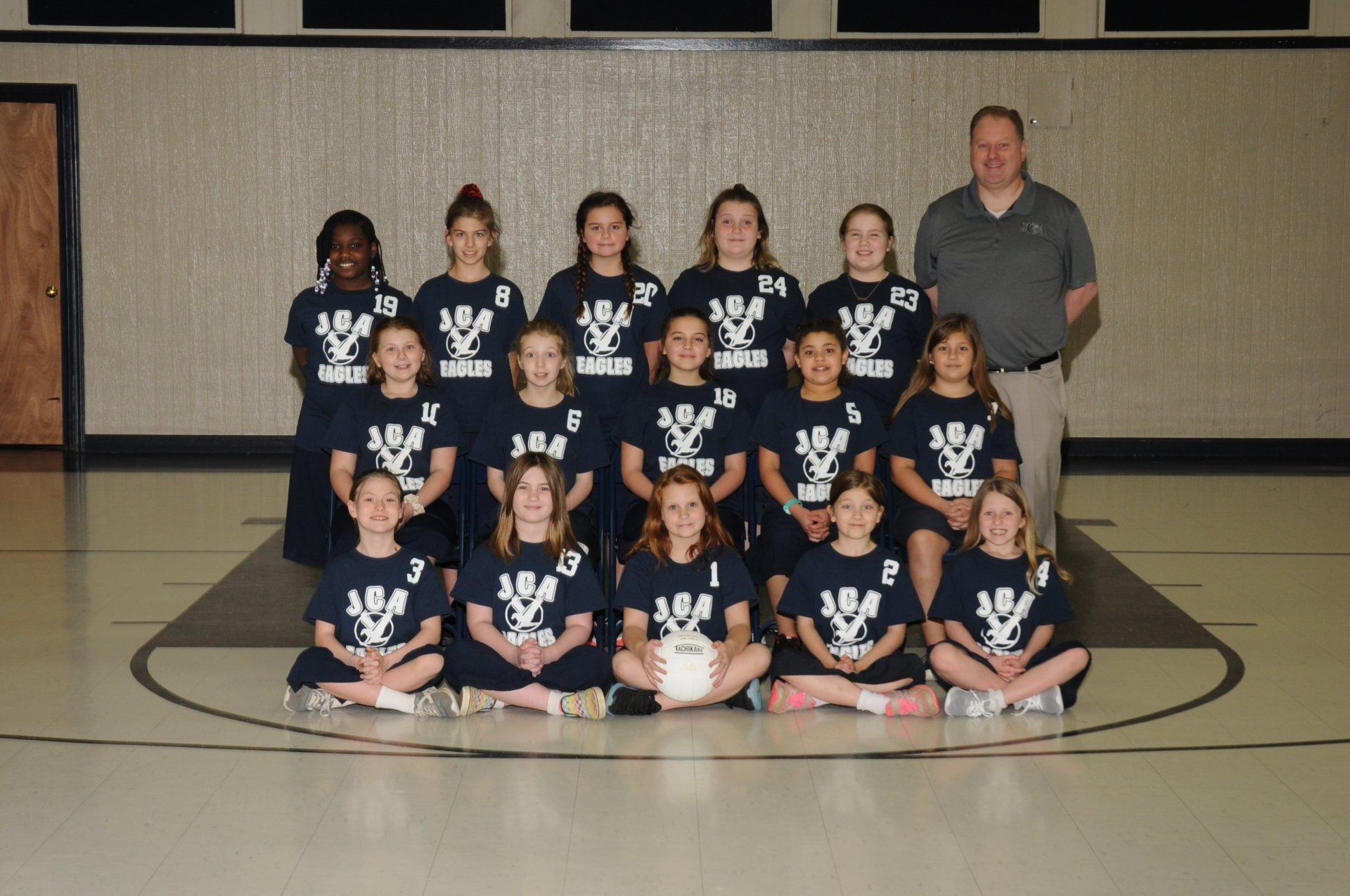 A group of young girls are posing for a picture in a gym.