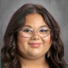 A close up of a woman wearing glasses and smiling.