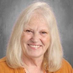 A woman with long blonde hair is smiling for the camera.