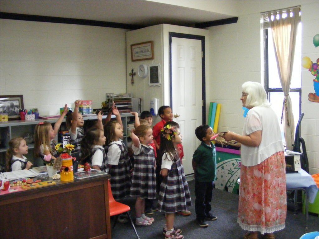 A woman is talking to a group of children in a classroom