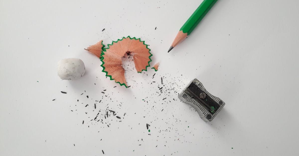 A green pencil is being sharpened on a white surface.