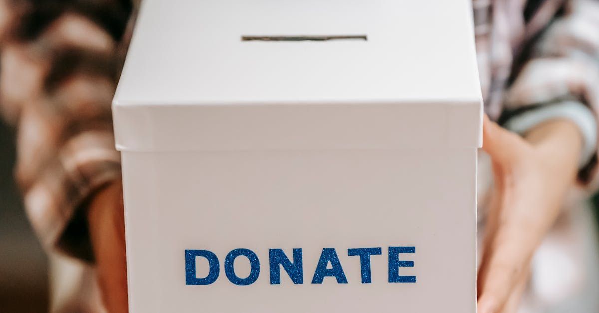 A person is holding a white box that says donate on it.