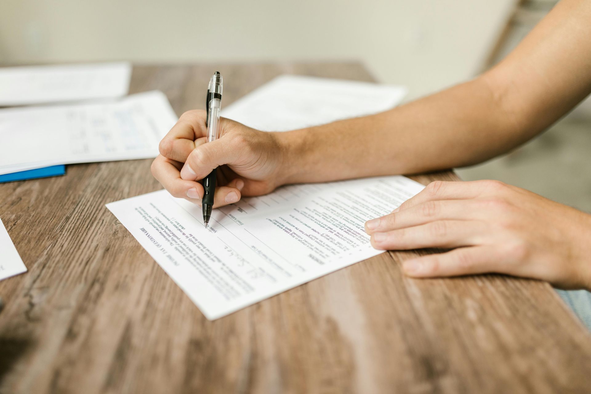 A person is writing on a piece of paper with a pen.