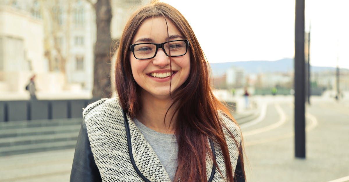 A young woman wearing glasses and a scarf is smiling for the camera.