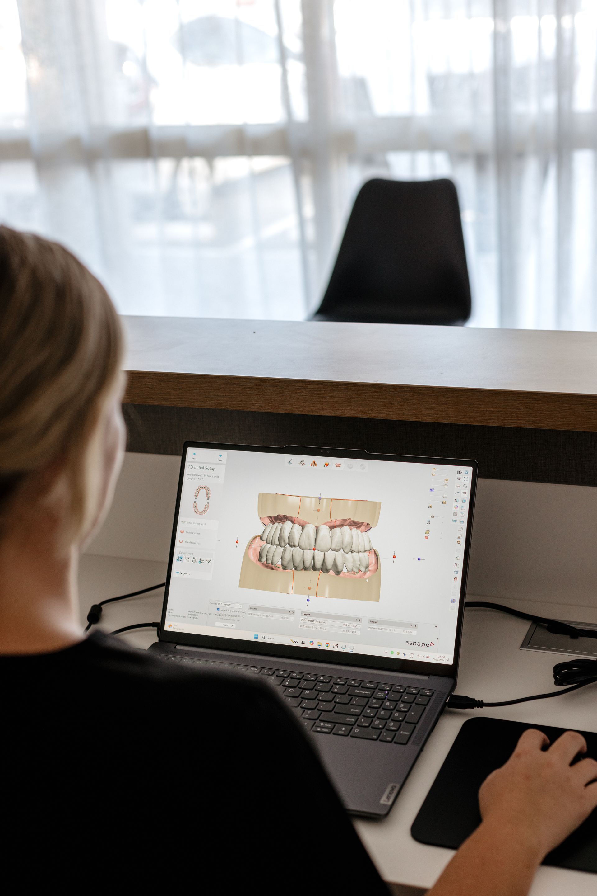 A Woman Is Sitting At A Desk In Front Of A Laptop Computer — Harvey Smiles Denture Clinic In Burleigh Heads, QLD