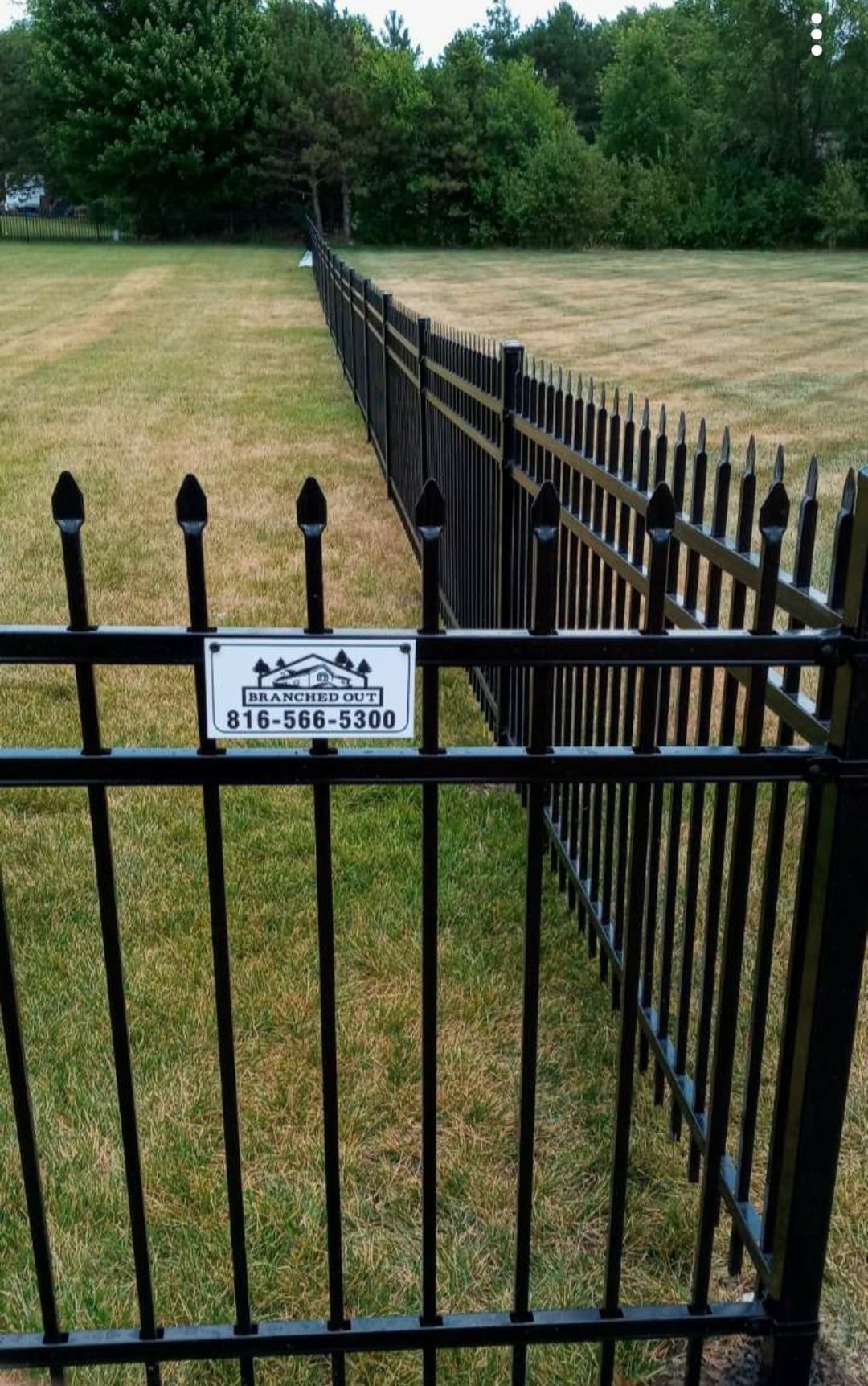 A black wrought iron fence surrounds a grassy field.
