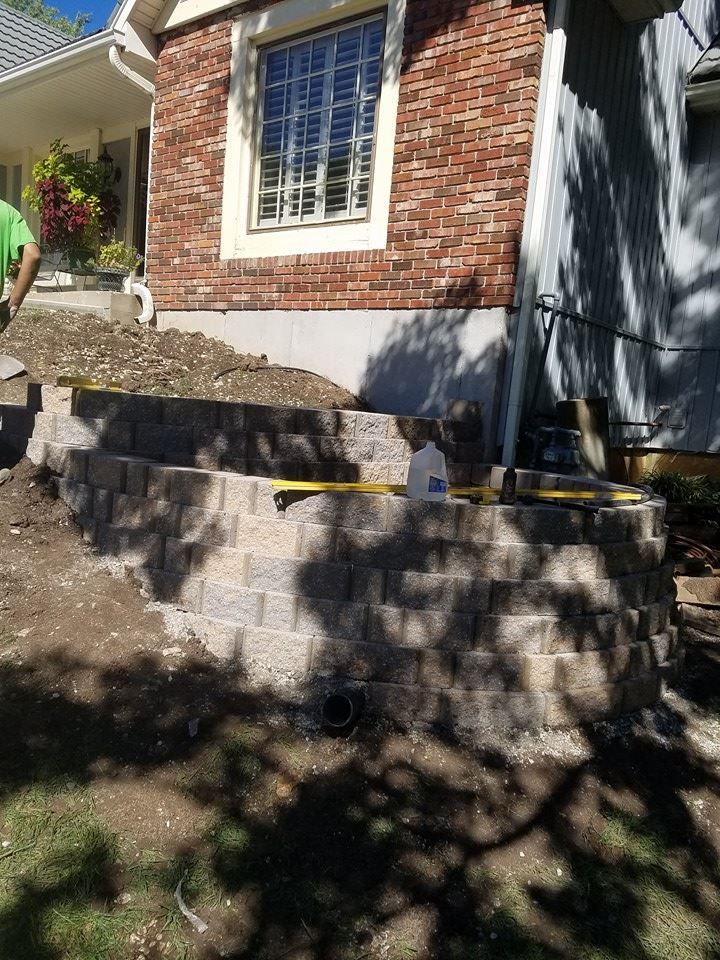 A brick wall is being built in front of a brick house.