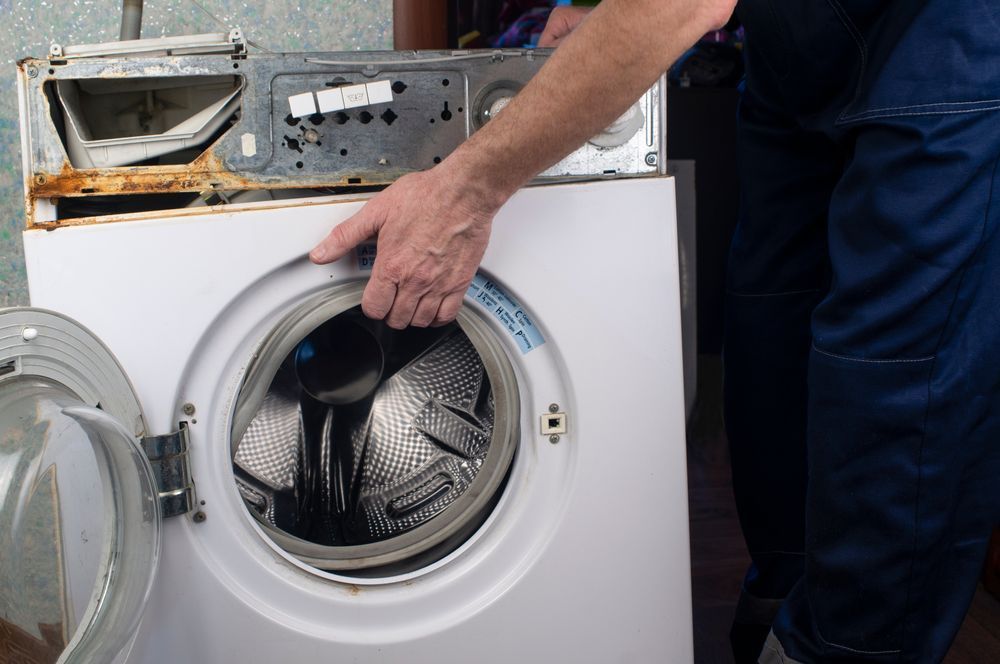 Person in Blue Work Pants Repairs a  White Washing Machine— Eurocoast Appliance Service In Tuggerah, NSW