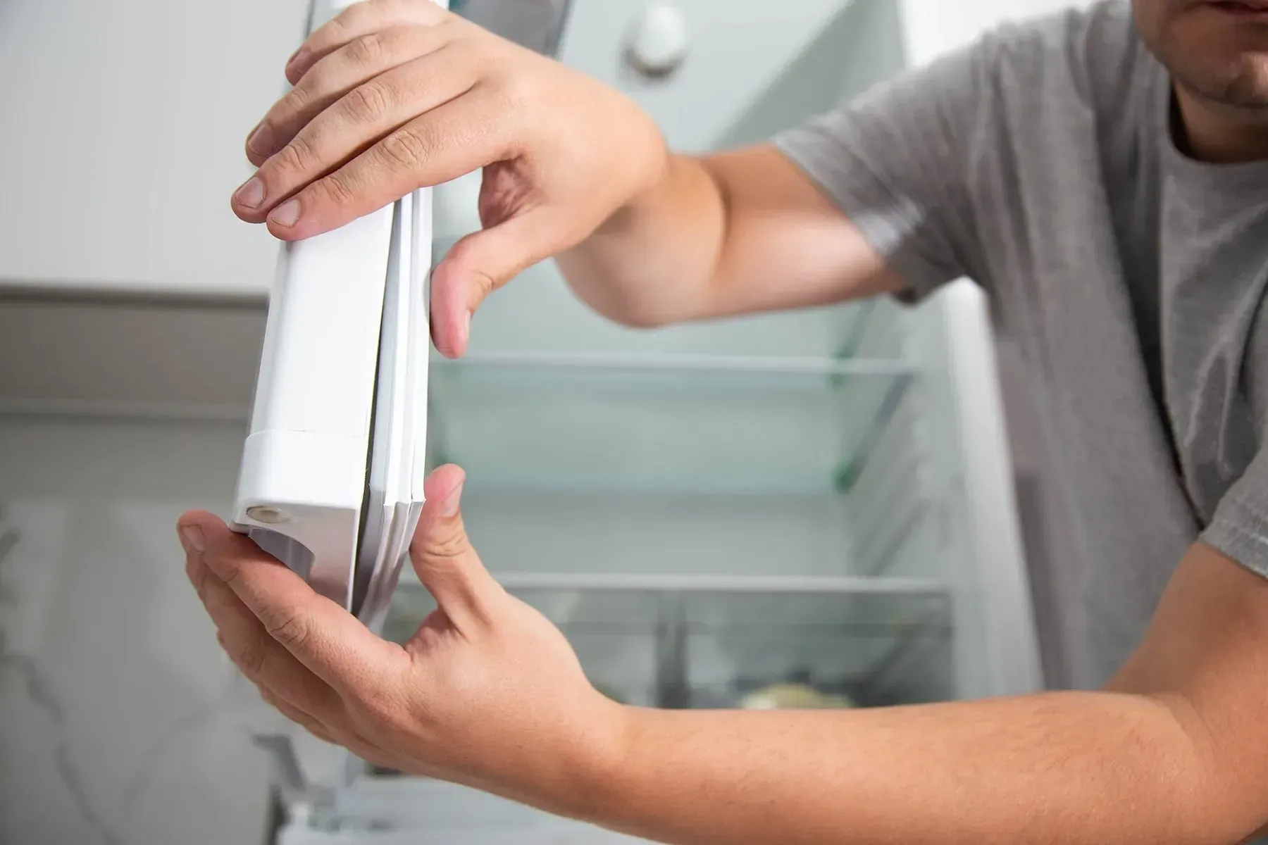 A Person Installing a New White Magnetic Door — Eurocoast Appliance Service In Wyong, NSW
