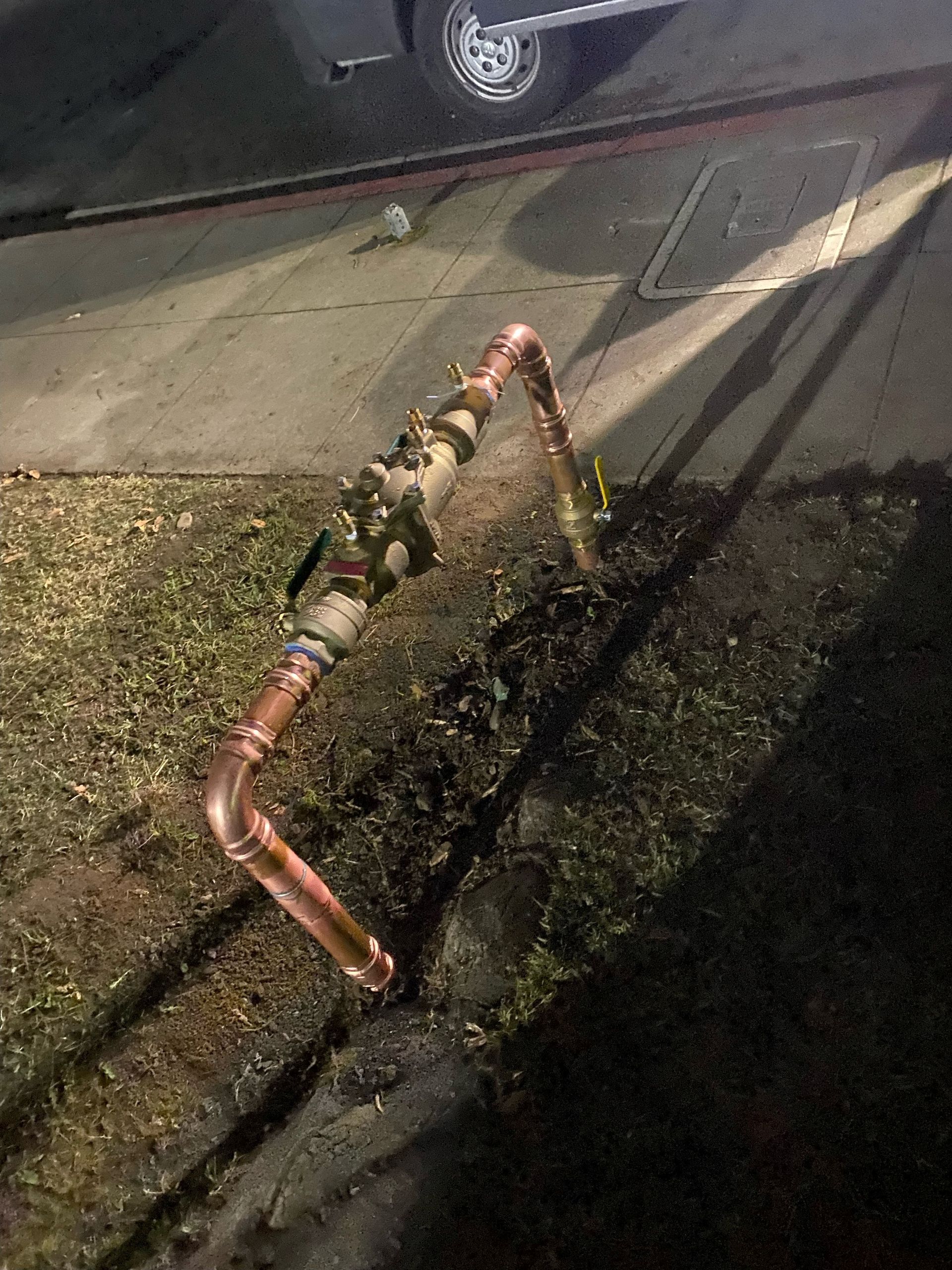 A copper pipe is sitting on the side of a road.