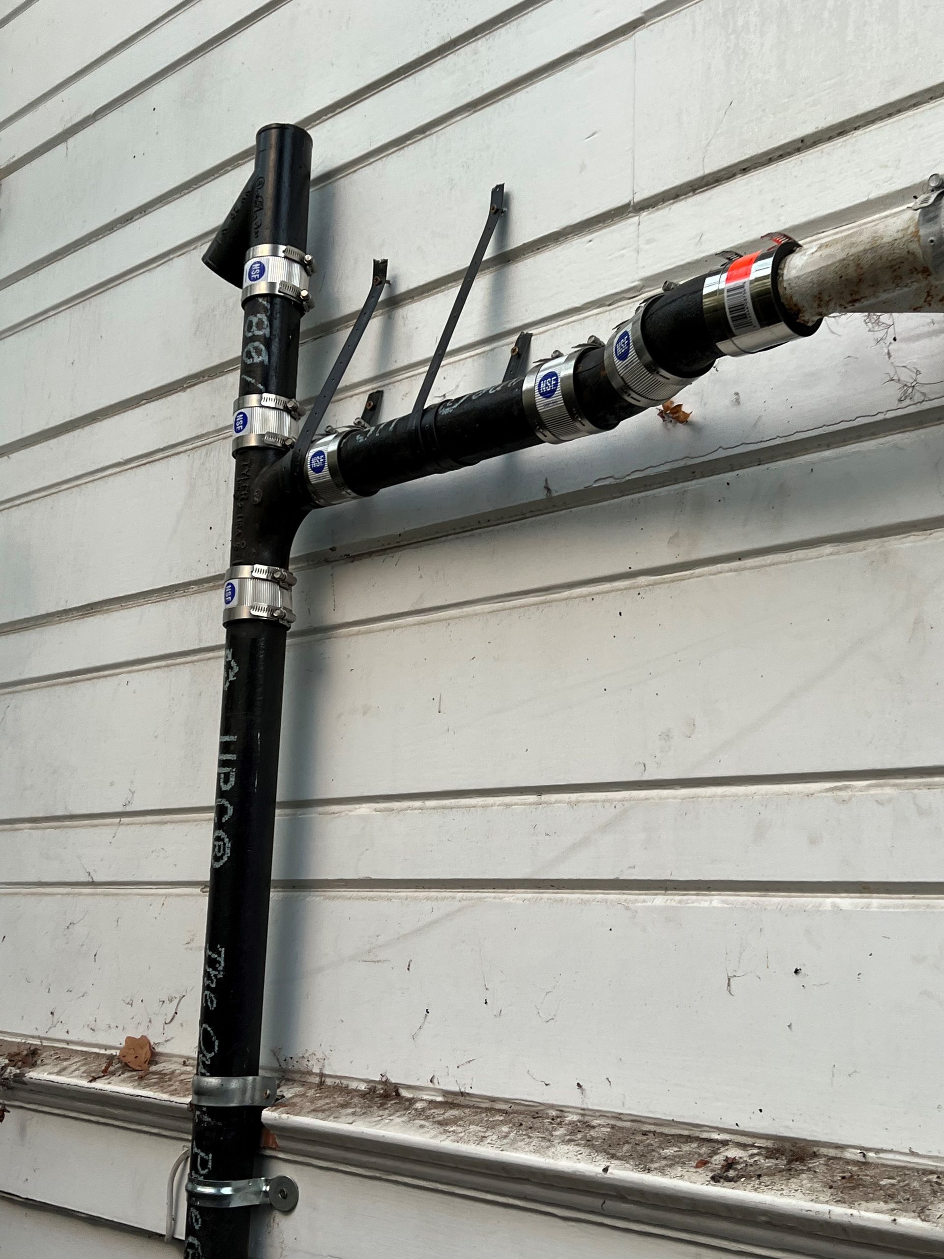 A black pipe is attached to a white wall